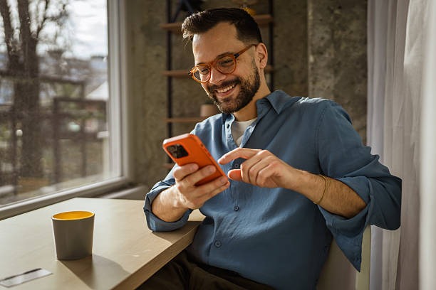 imageye imgi 33 smiling man using smart phone browsing online in cafe